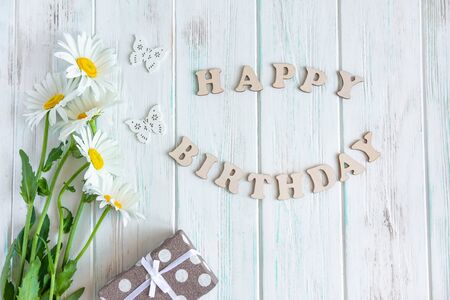Happy birthday greeting card with camomile flowers on wooden backgroundの写真素材