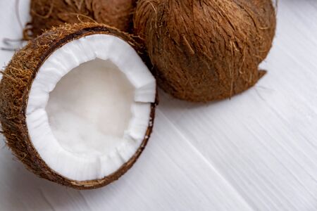 Half chopped coconut on a white wooden background. Tropical background with place for copy space. View from aboveの写真素材
