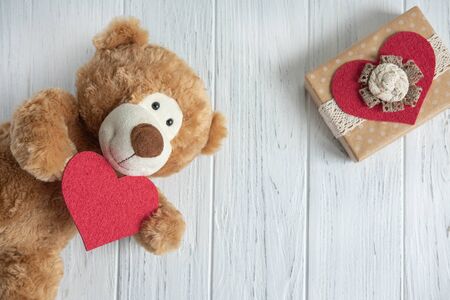Greeting card for birthday, mother's day, Valentine's day. Toy bear with hearts, gift boxes on a light wooden background.の写真素材