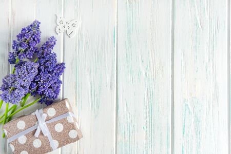 Spring flowers of lilac color with a gift box on a light wooden background. Greeting card with spring flowers.の写真素材
