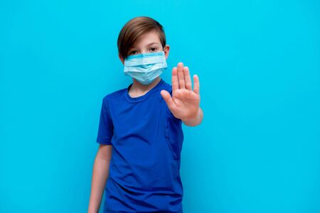 Stop coronavirus. A boy in a medical mask shows gestures of a foot illness.の写真素材