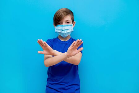 Stop coronavirus. A boy in a medical mask shows gestures of a foot illness.の写真素材