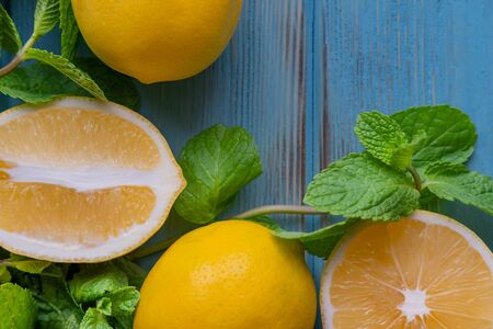 Closeup lemons cut in half on a blue wooden background with fresh mint leaves and place for an inscription. Citrus Vitamin Cの写真素材