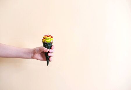Ice cream horn in a child's hand on a light monophonic background.の写真素材