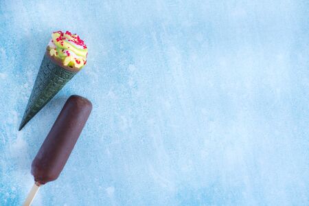 Ice cream in chocolate, ice cream cone with green waffle and bright crumbs. A few ice creams on a blue backgroundの写真素材