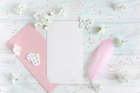Mock up with spring cherry flowers on a light wooden background. A letter with a pink envelope and a pen with a place for inscription. Top view congratulatory banner frameの写真素材