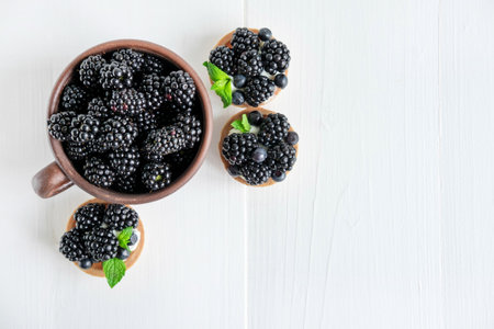 Blackberries and tartlets with blackberries top view on a wooden background with a place for an inscription. Blackberries and desserts with themの写真素材