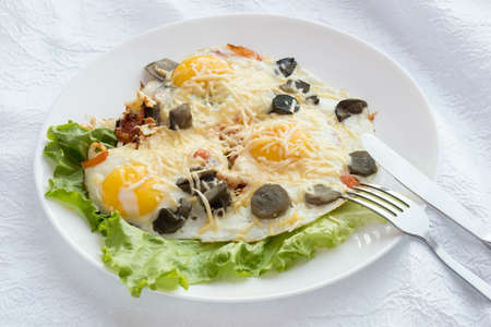 On the plate of eggs with a knife and fork.