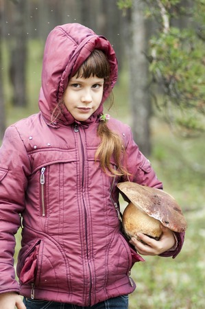Girl in the autumn forest holding a big white mushroom.の写真素材