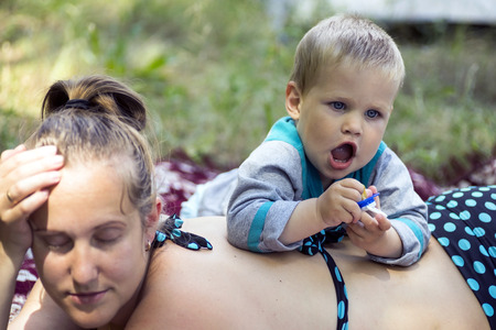 Young mother and son 1.3 years lying on the grass on a picnic.の写真素材