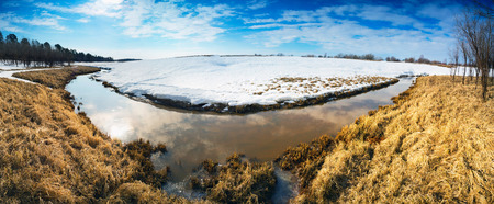 Spring landscape with a brook behind a snow mound . Siberia, Yugra.