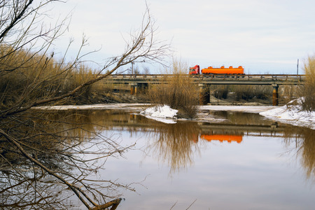 Truck driving on a bridge over a river in the spring.の写真素材