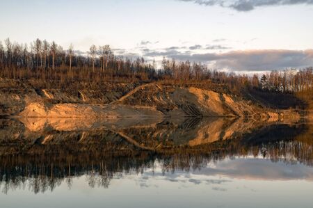 Mirror image in the lake of steep banks in spring. Vsevolozhsk. Leningrad region