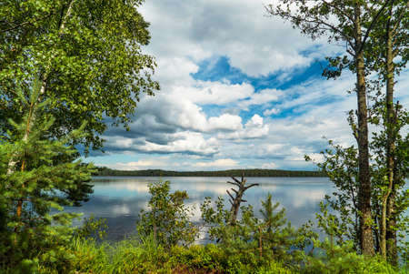 Lake with a mirror image on a Sunny day, blue sky and white clouds.の写真素材