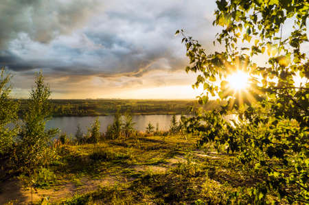 Thunderclouds and bright sun over a forest lake in summer.の写真素材
