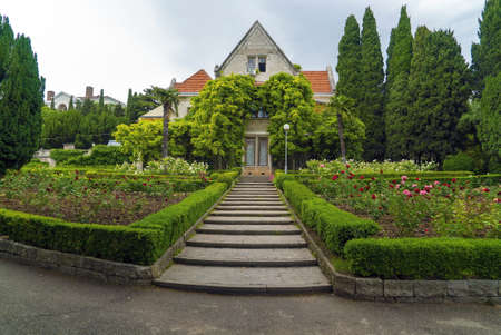 A flower bed and a path with steps at the house surrounded by greenery