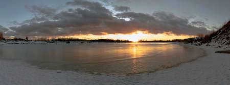 Sunset over a frozen lake. Winter landscape. Leningrad region.の写真素材