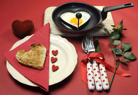 Red theme Valentine breakfast with heart shape egg and toast with love hearts on red background の写真素材