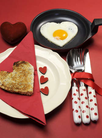 Red theme Valentine breakfast with heart shape egg and toast with love hearts on red background の写真素材