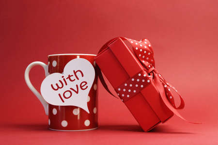  With love  message on red polka dot mug and red gift with polka dot ribbon bow against a red background for a bright, fun and cheerful Valentines Day or special gift of love の写真素材