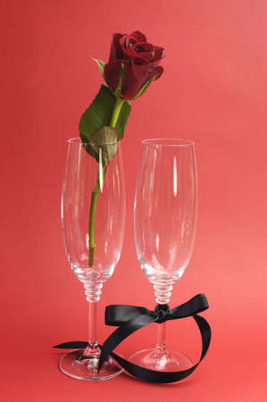 Red rose in champagne glasses for special occasion or Valentines Day against a red background to say I love You の写真素材