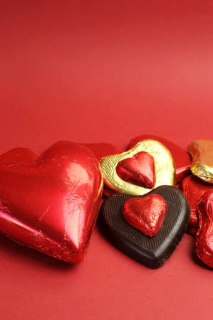 Red and gold wrapped chocolates against a red background for Valentine or saying I love You, with copy space の写真素材