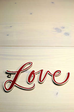 The word, Love, spelled in red script letters on white shabby chic table, vertical with copy space の写真素材