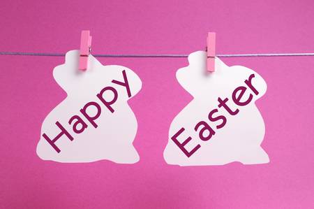 Two bunny rabbit shape Easter cards hanging from pegs on a line, with Happy Easter message in pink の写真素材