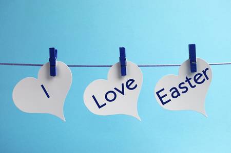 I Love Easter message written across 3 heart tags hanging from pegs on a line against a blue background の写真素材