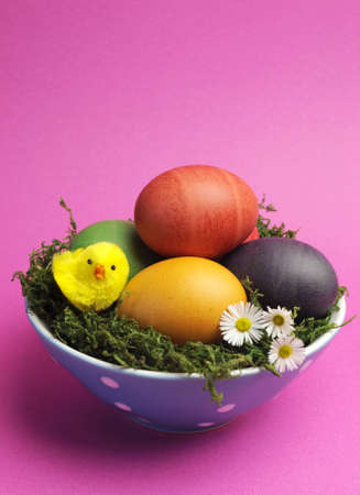 Bright and cheerful Happy Easter still life with rainbow color eggs in blue polka dot bowl against a pink background - vertical with copy space の写真素材