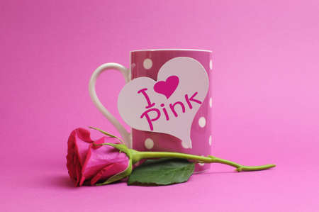 I love  heart  pink  message written on a white heart sign on a pink polka dot coffee mug with a pink rose bud against a pink background の写真素材
