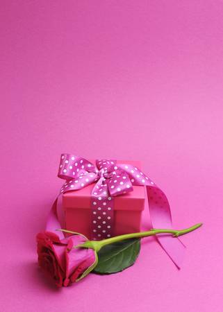 Pretty pink gift with polka dot pink ribbon and pink rose against a pink background  Vertical portrait orientation, with copy space for your text here の写真素材