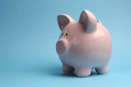 Pretty pink piggy bank against a blue background for Savings and Shopping Sale concept, with copy space for your text here の写真素材