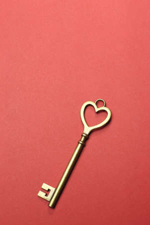 Heart shape key for  keys to my heart ,  keys to my success  or business  key performance indicators  concept, on red background  Vertical with copy space for your text here の写真素材