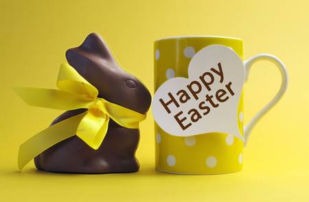 Yellow theme polka dot breakfast coffee mug with chocolate bunny rabbit and heart shape message saying Happy Easter.の写真素材