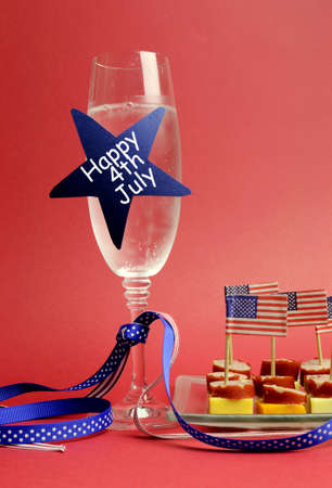 USA Happy Fourth 4th of July party table setting with flags, ribbons, polka dots, and stars and stripes champagne glass and cocktail food  Vertical の写真素材