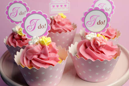 Pink wedding cupcakes with I Do topper signs on pink cake stand - close up.の写真素材