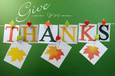 Give Thanks message spelling in letters hanging from pegs on a line for Thanksgiving greeting in autumn colors, with autumn fall leavesの写真素材
