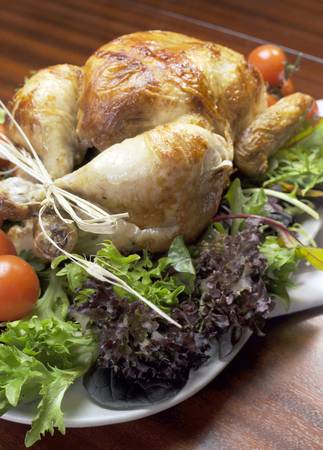 Platter of delicious roast chicken turkey with salad greens and red tomatoes on the vine for a succulent, delicious Christmas or Thanksgiving lunch or dinner meal  Vertical の写真素材