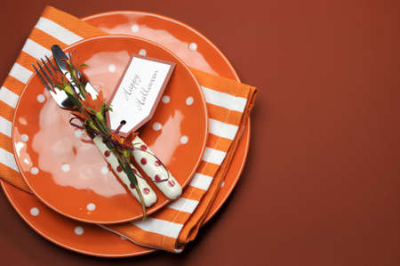 Bright and modern Happy Halloween orange polka dot and stripes plates and napkins lunch or dinner table setting, with copy space for your text here.の写真素材
