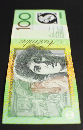Australian green and gold  100 hundred dollar note, against a black background  vertical 