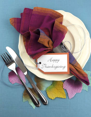 Modern Thanksgiving dining table place setting on aqua blue tablecloth, with material autumn leaves, in pink blue and orange theme. Vertical aerial view. Modern Thanksgiving dining table place setting on aqua blue tablecloth, with material autumn leaves, in pink blue and orange theme. Vertical aerial view.