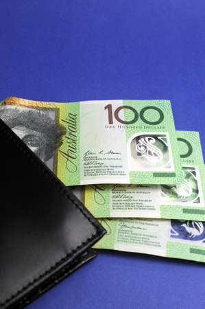 Three hundred Australian dollar green and yellow notes folding out from black wallet. Vertical.