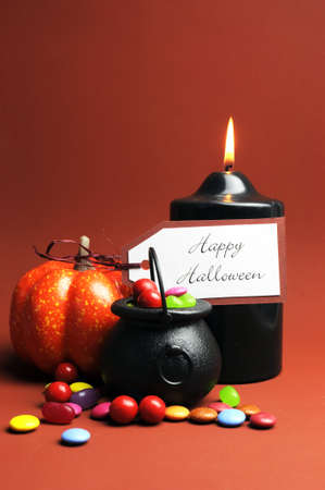 Halloween Trick or Treat witches cauldrons full of candy on autumn brown background with black candle and orange pumpkin Vertical with copy space for your text here  の写真素材