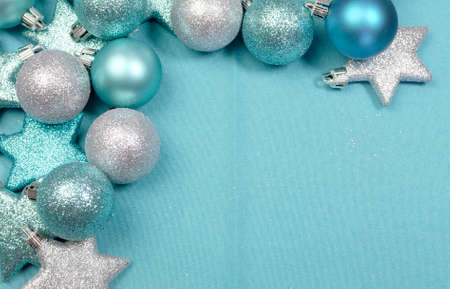 Festive background of aqua torquiose pale blue christmas glitter baubles and stars on a pale aqua blue material tablecloth background, with copy space,の写真素材
