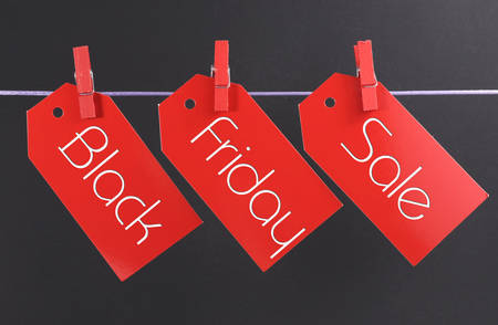 Black Friday shopping sale concept with message written across red ticket sale tags hanging from pegs on a lineの写真素材