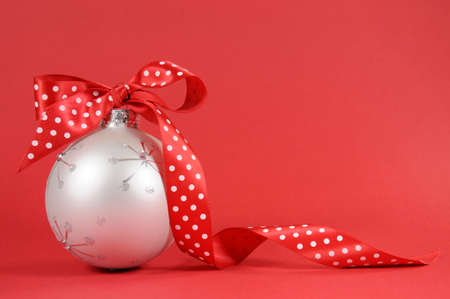 Close up of beautiful white Christmas tree ornament with red polka dot ribbon on redの写真素材