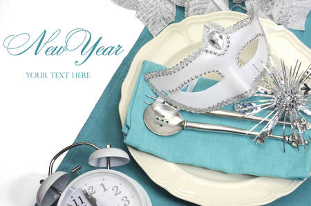 Bring in the New Year dining table place setting with masquerade mask, retro vintage pocket watch clock and fine china and antique silverware in a aqua blue and white theme.の写真素材