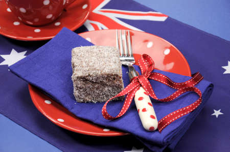 Australia Day, Anzac Day or Australian public holiday or national event dining table place setting with polka dot china and Australian flag, in red, white and blue theme colors, with a lamington on a plate close up.の写真素材