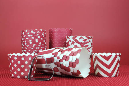 Red Valentine, wedding, birthday or love theme cupcake patty pan paper cups with heart cookie cutter on red background の写真素材